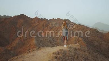站在山顶上的年轻金发女人。 带日落的山景，慢动作，4k